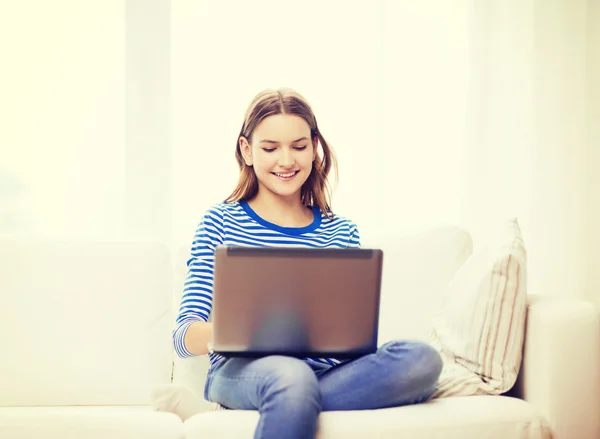 Sonriente adolescente con ordenador portátil en casa —  Fotos de Stock