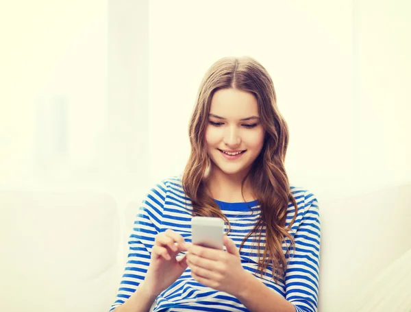 Smiling teenage girl with smartphone at home — Stock Photo, Image