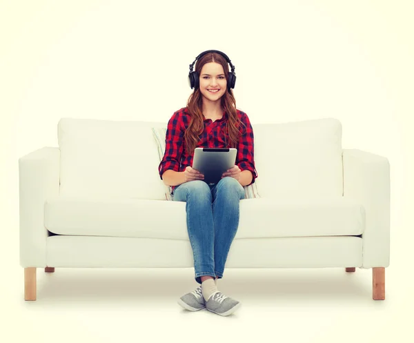 Chica sentada en el sofá con auriculares y tablet PC — Foto de Stock