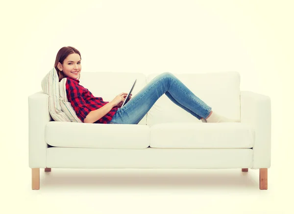 Девочка-подросток, сидящая на диване с планшетным компьютером — стоковое фото