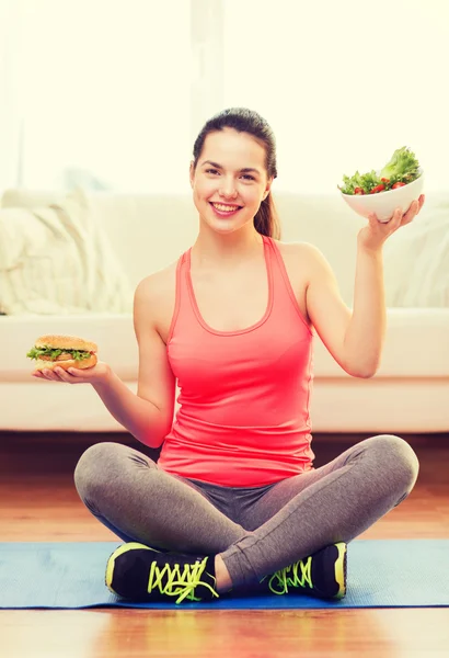 Lachende tiener met groene salade en hamburger — Stockfoto