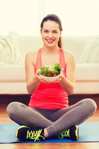 Lächelndes Teenager-Mädchen mit grünem Salat zu Hause — Stockfoto