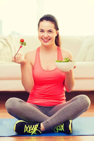 Lächelndes Teenager-Mädchen mit grünem Salat zu Hause — Stockfoto