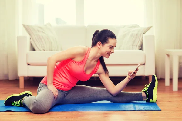 Smiling teenage girl streching on floor at home — Stock Photo, Image