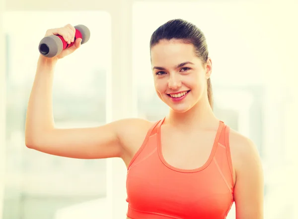 Smiling teenage girl exercising with dumbbell — Stok fotoğraf