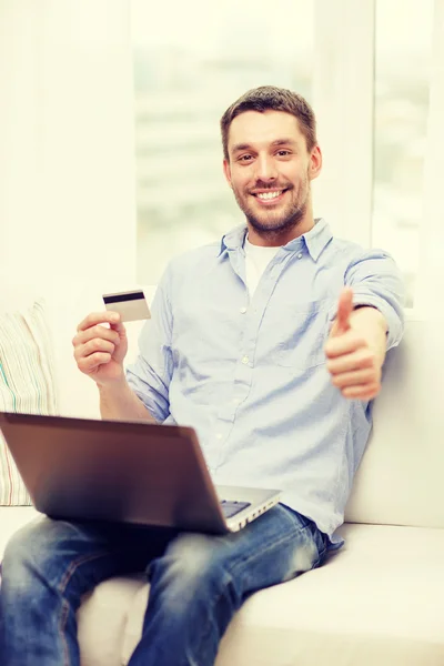 Uomo sorridente che lavora con laptop e carta di credito — Foto Stock