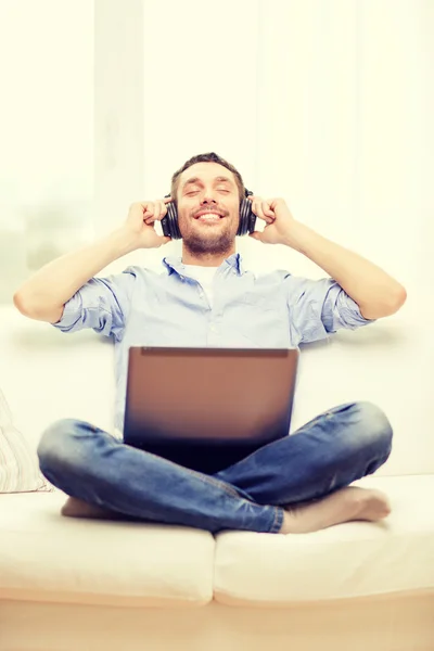 Glimlachende man met laptop en hoofdtelefoon thuis — Stockfoto