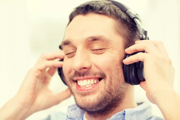 Joven sonriente con auriculares en casa — Foto de Stock