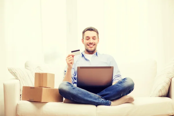 Man with laptop, credit card and cardboard boxes — Stock Photo, Image