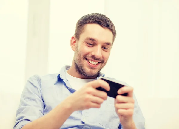 Glimlachende man met smartphone thuis — Stockfoto