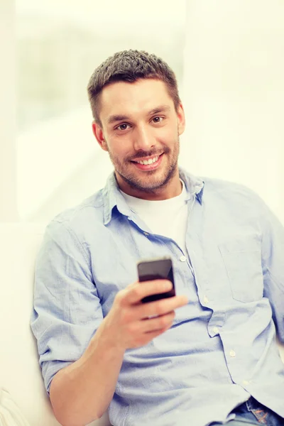 Hombre sonriente con smartphone en casa — Foto de Stock