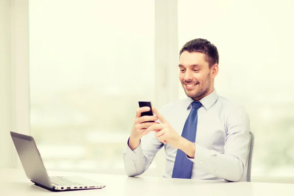 Homme d'affaires avec ordinateur portable et smartphone au bureau — Photo