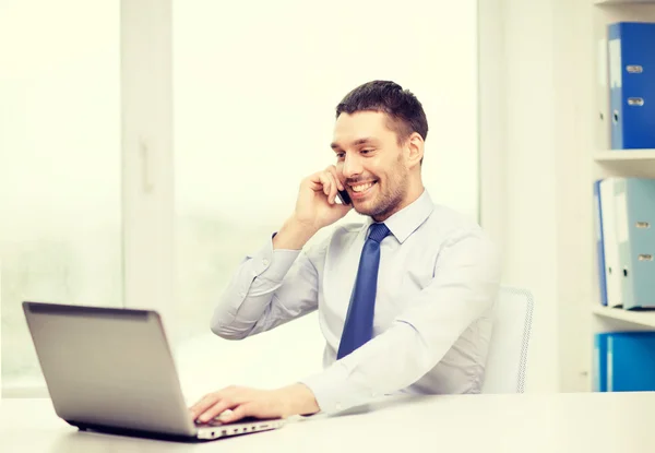 Empresario con computadora portátil y teléfono inteligente en la oficina — Foto de Stock