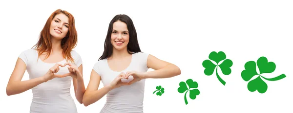 Meninas sorridentes mostrando gesto do coração com shamrock — Fotografia de Stock