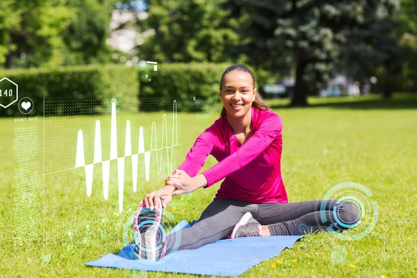 Mujer sonriente estirando la pierna en la estera al aire libre —  Fotos de Stock