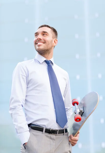 Jonge lachende zakenman met skateboard buitenshuis — Stockfoto