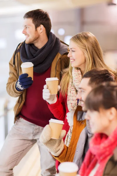 Amis heureux avec tasses à café sur patinoire — Photo