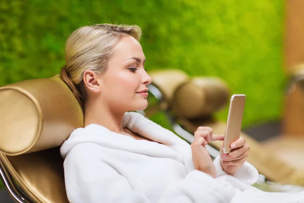 Mooie jonge vrouw met smartphone in spa — Stockfoto