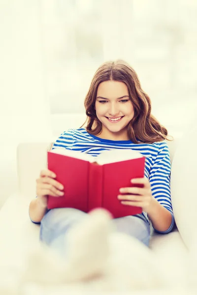 Usmíval se dospívající dívka čtení knih na gauči Royalty Free Stock Obrázky