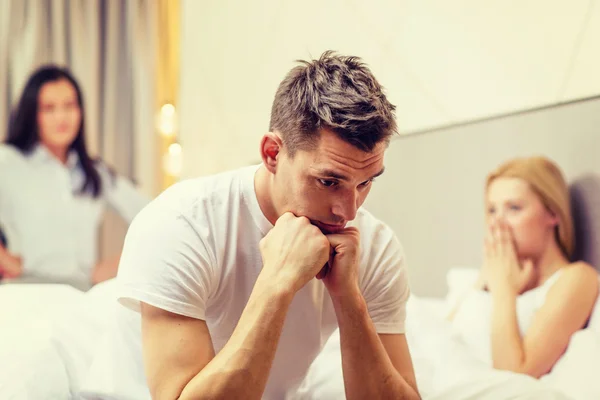 Mann sitzt auf dem Bett mit zwei Frauen auf dem Rücken — Stockfoto