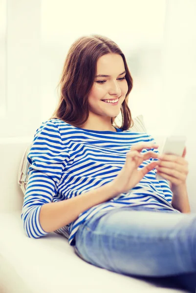 Lachende tienermeisje met smartphone thuis — Stockfoto