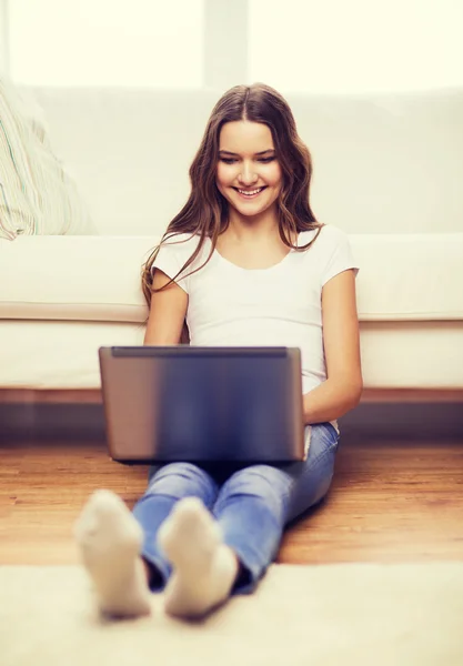 Sonriente adolescente con ordenador portátil en casa —  Fotos de Stock