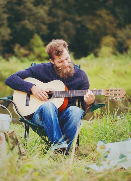 Smiling man with guitar and dixie in camping — Stock Photo, Image