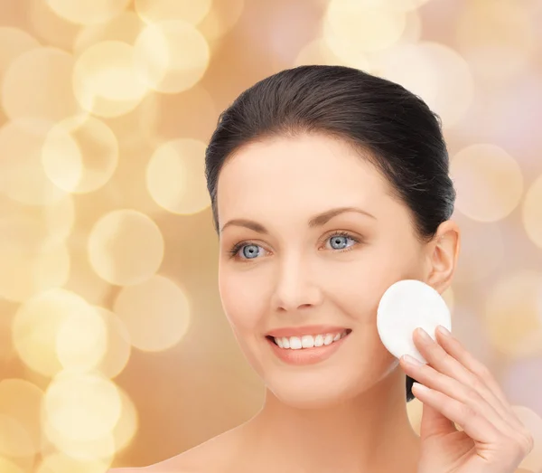 Mujer sonriente limpiando la piel de la cara con algodón —  Fotos de Stock