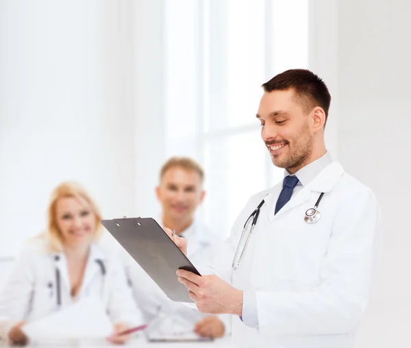 Sonriente médico varón con portapapeles y estetoscopio — Foto de Stock