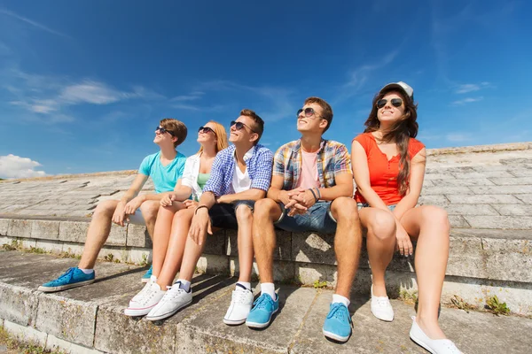 Grupo de amigos sonriendo sentados en la calle de la ciudad — Foto de Stock