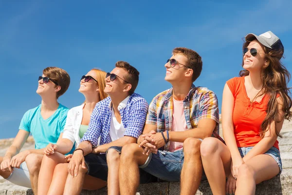 Group of smiling friends sitting on city street — Stock Photo, Image