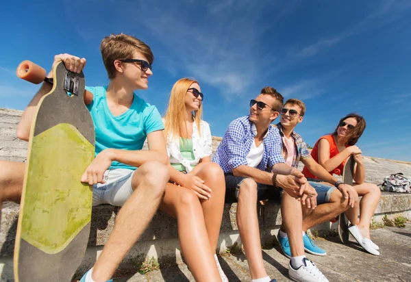 Group of smiling friends sitting on city street — Stock Photo, Image