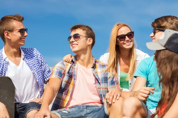 Group of smiling friends sitting on city street — Stock Photo, Image