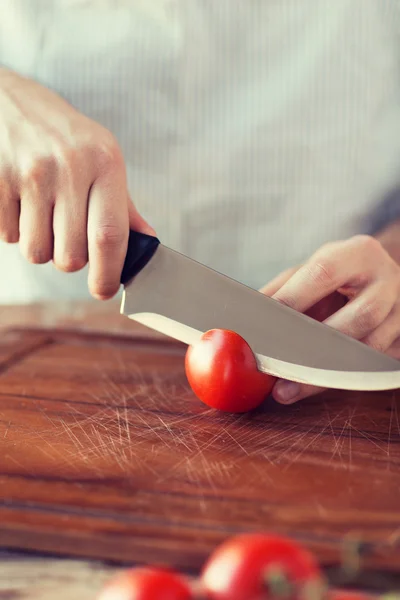 Male hand cutting tomato on board with knife — Stock Photo, Image