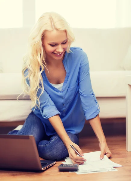 Femme souriante avec papiers, ordinateur portable et calculatrice — Photo