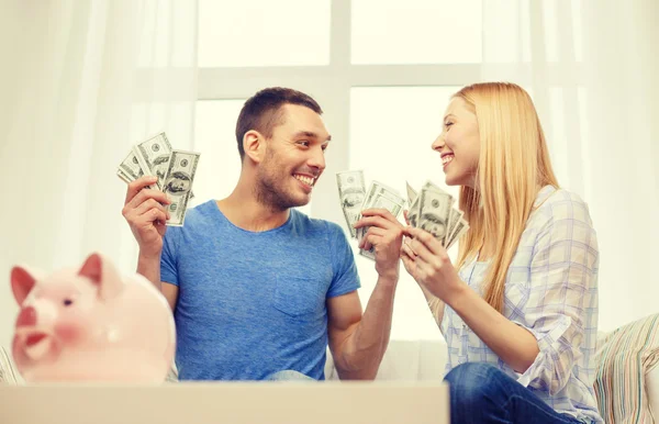 Couple with money and piggybank ot table at home — Stock Photo, Image