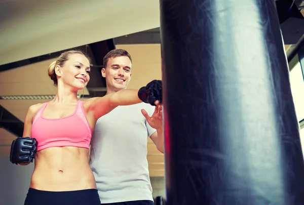 Lächelnde Frau mit Personal Trainer beim Boxen im Fitnessstudio — Stockfoto