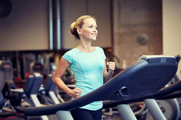 Улыбающаяся женщина, упражняющаяся на беговой дорожке в спортзале — стоковое фото