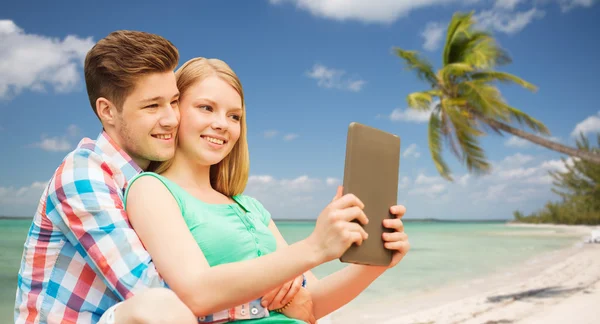 Пара с планшетным ПК принимая селфи над пляжем — стоковое фото