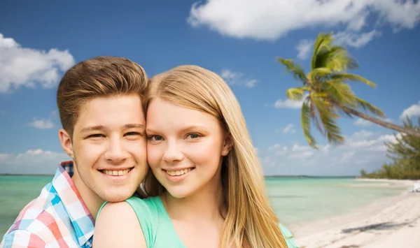 Sonriente pareja abrazándose sobre playa fondo —  Fotos de Stock