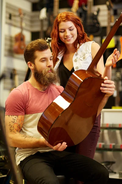 Couple of musicians with guitar at music store — Stock Photo, Image