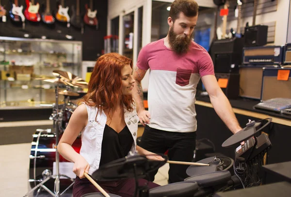 Hombre y mujer con kit de batería en la tienda de música — Foto de Stock