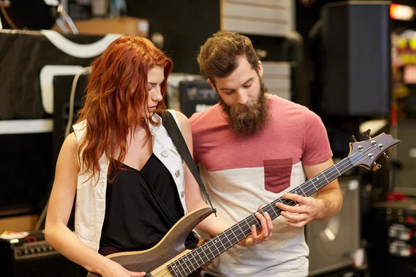 Музыканты играют на бас-гитаре в музыкальном магазине — стоковое фото