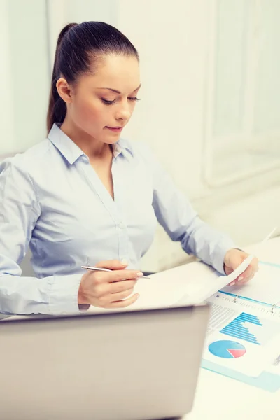 Geschäftsfrau mit Laptop und Charts im Büro — Stockfoto