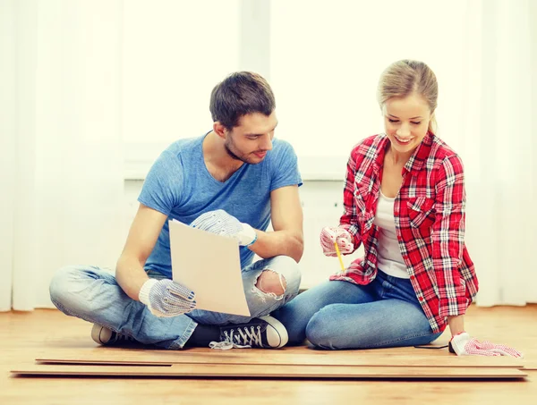 Pareja sonriente midiendo pisos de madera —  Fotos de Stock