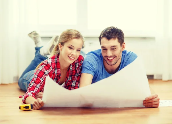 Smiling couple looking at blueprint at home — Stock Photo, Image