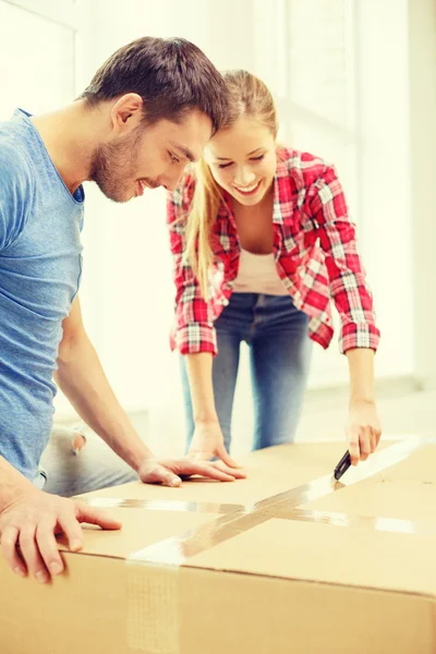 Smiling couple opening big cardboard box — Stock Photo, Image