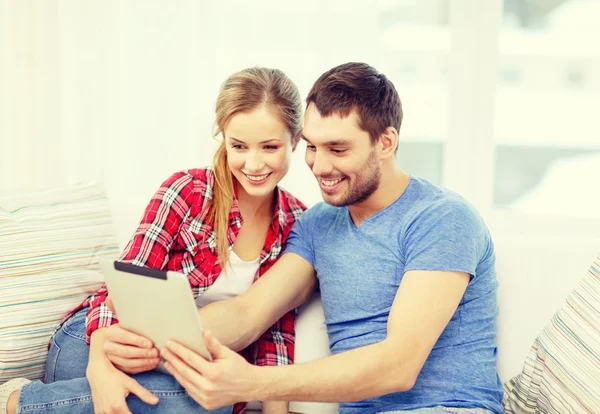 Улыбающаяся пара с планшетным компьютером дома — стоковое фото