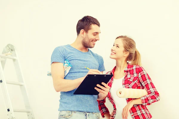 Couple souriant avec presse-papiers et rouleau de papier peint — Photo