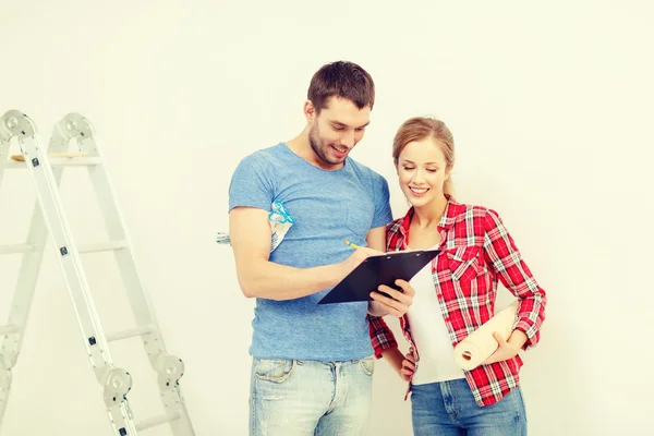 Smiling couple with clipboard and wallpaper roll — Stock Photo, Image